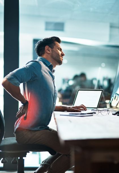 Employee with back pain at desk - Workplace Health & Wellness